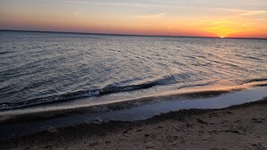 A beach at sunset with waves gently lapping onto the shore.