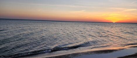A beach at sunset with waves gently lapping onto the shore.