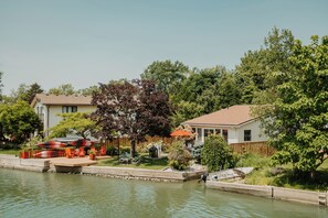 Zona residencial con una casa, un muelle y un barco pequeño.