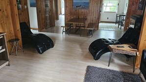A wooden-paneled room with a dining table, two black leather sofas, and a small wooden table with a laptop.