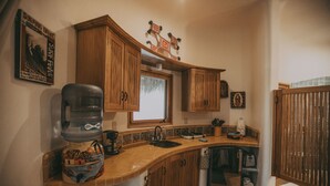 A kitchen with wooden cabinets, a water dispenser, a sink, and a window. - Casa Coco  Ocean/Jungle view Studio (Sayulita)