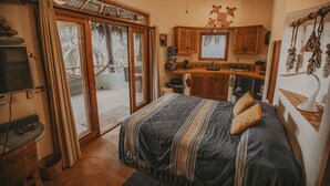 A bedroom with a large bed, a TV, and a sliding glass door leading to a balcony. - Casa Coco  Ocean/Jungle view Studio (Sayulita)