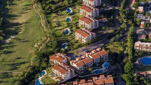 Vista aérea de un resort con varias edificaciones, piscinas y una playa.
