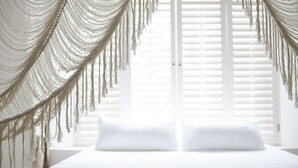 Una cama con ropa de cama blanca y un dosel de macramé.