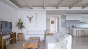 Una sala de estar moderna con un sofá, una mesa de centro, televisor y una planta en maceta.