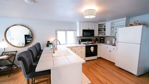 A modern kitchen with a central island, white cabinetry, and a microwave. - Cozy Turns- Vail/ Minturn Colorado (Minturn)