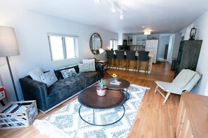 A modern living room with a dark leather sofa, two round coffee tables, and a wooden cabinet.