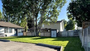 A residential backyard with a lawn, a wooden fence, and a house.