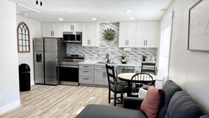 A modern kitchen with white cabinets, stainless steel appliances, and a gray backsplash.