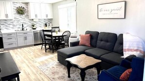 A modern living room with a sectional sofa, a coffee table, and a dining area with a table and chairs.