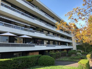 A multi-story building with balconies, outdoor seating, and greenery.
