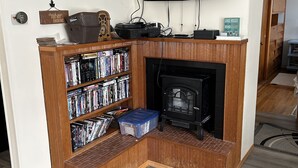 Ein Wohnzimmer mit Kamin, einem darüber montierten Fernseher, einem Bücherregal und einem Teppich.