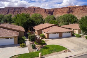 A residential area with houses featuring red-tiled roofs, surrounded by green trees and a mountainous backdrop. - Private Spa | Art Lover's Dream | Pool | Garage | Close to Parks | C401 (Moab)