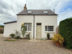 A two-story white house with a grey roof, a front door, and two windows on the ground floor. - Robins Nest Cottage (Blairgowrie)