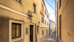 Una calle estrecha flanqueada por edificios, con un banco y una unidad de aire acondicionado en la pared.