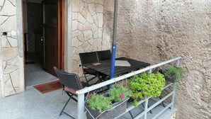Un patio con una mesa y sillas, una planta en maceta y un muro de piedra.