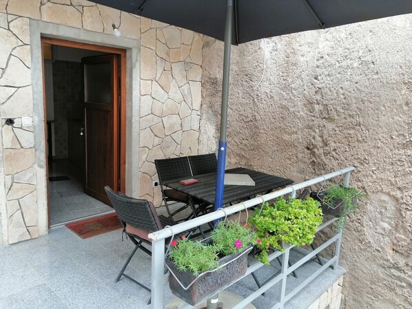 A patio with a table and chairs, a potted plant, and a stone wall.