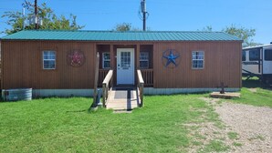 A wooden building with a green roof, a front door, and a star decoration on the wall. - Safari-ish Cabin Getaway in Jacksboro (Jacksboro)