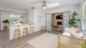 Un'ampia cucina con isola centrale, sgabelli di legno e ventilatore a soffitto.