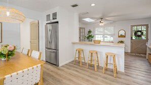 Una cucina moderna con frigorifero in acciaio inox, un tavolo da pranzo in legno con sedie e un'area bar con sgabelli.