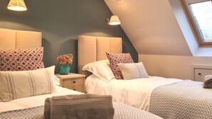 Ein Schlafzimmer mit zwei Betten, einem Nachttisch, einer Vase mit Blumen und einem Fenster.
