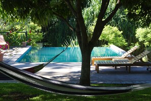 A pool area with a hammock, lounge chairs, and a tree. - Guácima Escondida Hotel Boutique (Guacima)