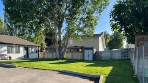 Un patio trasero residencial con césped, una terraza de madera y una casa.