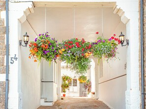 A corridor with hanging flower baskets and wall-mounted lanterns. - The Coach House at Vane Hill (Torquay)