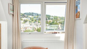 Une pièce avec une grande fenêtre, un radiateur et un seul fauteuil orange.