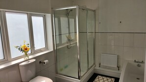 A bathroom with a glass-enclosed shower, a toilet, a sink, and a window with a vase of flowers. - Victoria Heights - Beautiful 3-bed in Gillingham K (Gillingham)