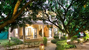 A building with a staircase leading to a balcony, surrounded by greenery and a pathway. - Corbett Aroma Park By Royal Collection (Ramnagar)