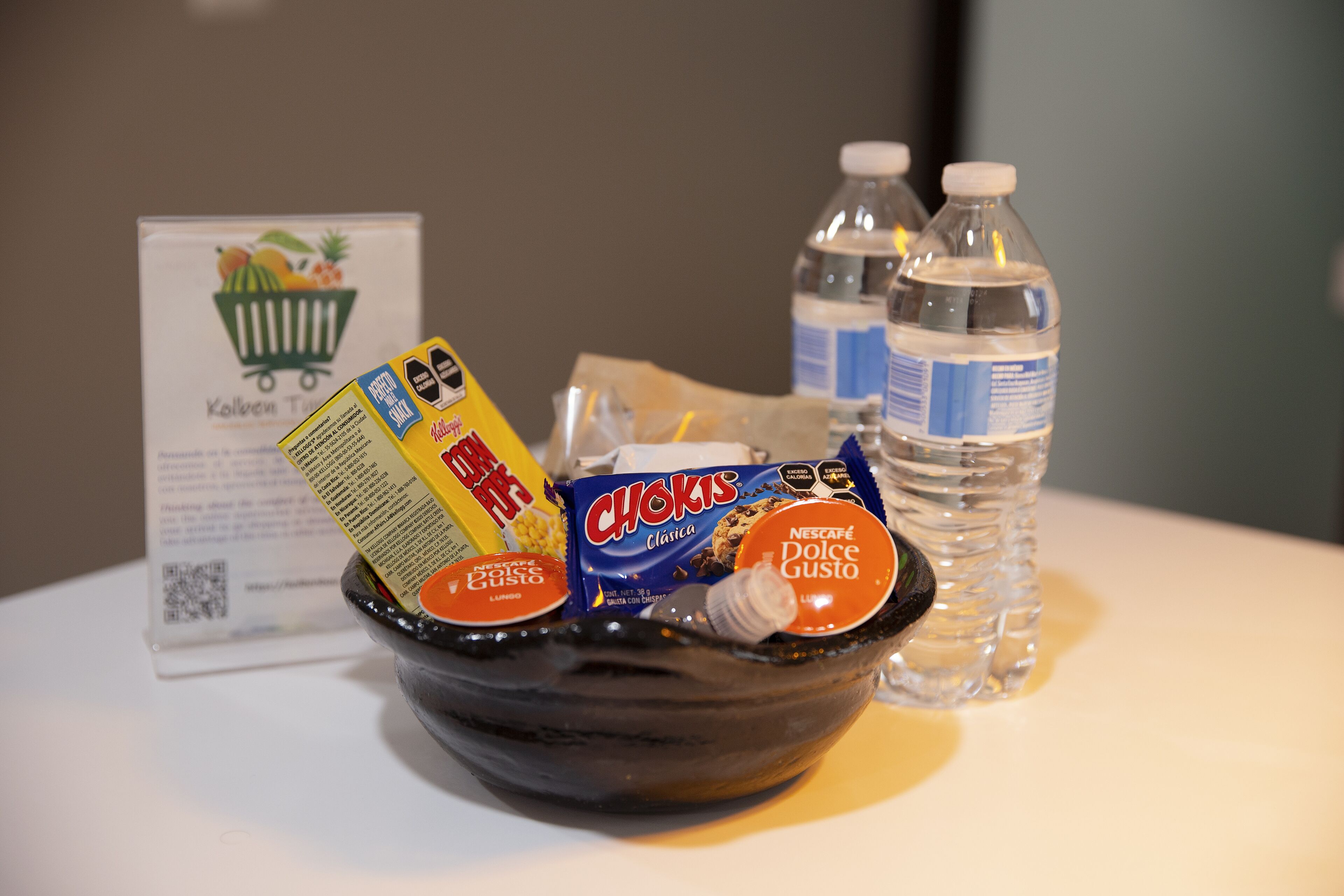 A bowl containing various food items and a water bottle on a table.