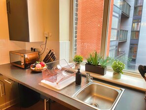 A kitchen with a microwave, toaster, sink, and potted plants.