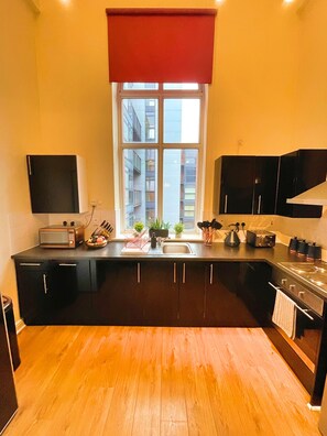 A modern kitchen with black cabinets, a microwave, a sink, and a stove.