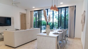 A modern kitchen with a central island, large windows, and a dining area with chairs and a table. - Hunab Tulum (Tulum)