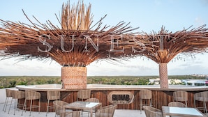 An outdoor bar area with wicker furniture and a brick fireplace. - Hunab Tulum (Tulum)
