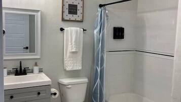 Une salle de bain avec des toilettes, un lavabo et une douche.