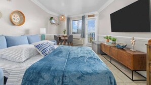 A bedroom with a bed, a desk, a chair, a TV, and a window. - Renovated Condo with Gorgeous Ocean Views (Myrtle Beach)