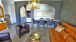 A modern living room with a leather sofa, a coffee table, and a dining area with chairs and a table. - R1358 | La Hacienda 10 | Burriana (Nerja)