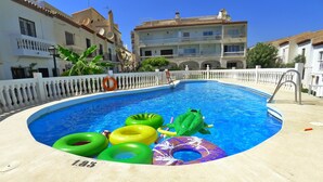 A swimming pool with inflatable rings, a pool ladder, and a white fence. - R1358 | La Hacienda 10 | Burriana (Nerja)