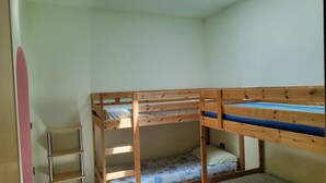 A bunk bed room with a skylight, a small shelf, and a tiled floor.