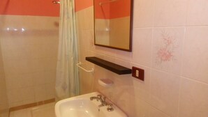 A bathroom with a white sink, a mirror, a towel rack, and a shower curtain.