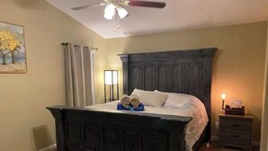 Ein Schlafzimmer mit einem dunklen Holzbett, einem Nachttisch mit Lampe und einem Bild an der Wand.
