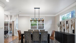 A dining area with a rectangular table, six chairs, and a modern pendant light.