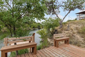 Eine Holzterrasse mit Bänken, die auf einen Fluss mit Bäumen und Vegetation blickt.