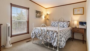 A bedroom with a bed, bedside table, lamp, and a window with blinds. - Hondo Creek Hideaway (Tarpley)
