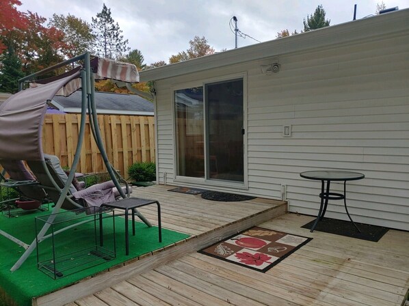 A covered patio with a swing set, a small table, and a sliding glass door leading to a covered area.