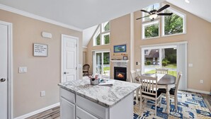A kitchen with a marble countertop, a fireplace, and a dining area with chairs.