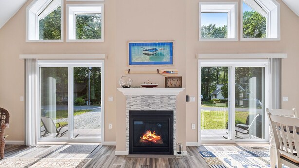 A spacious living room with a fireplace, large windows, and a view of the outdoors.