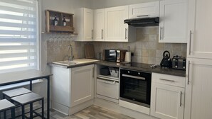 Una cocina moderna con armarios blancos, un horno negro, un microondas y un tostador.